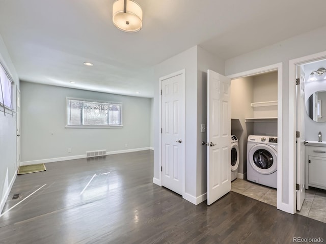 washroom with sink, dark hardwood / wood-style flooring, and washing machine and clothes dryer