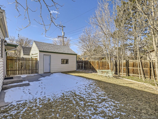 yard covered in snow with an outbuilding and a patio