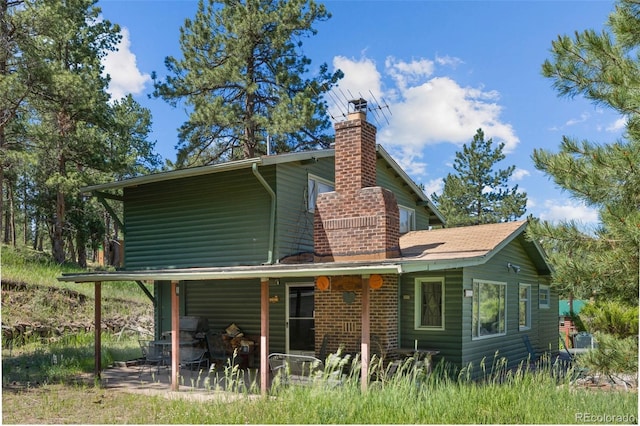 2598 S Platte River Rd, Sedalia, CO 80135 - back of house with a chimney, a patio area, and log veneer siding