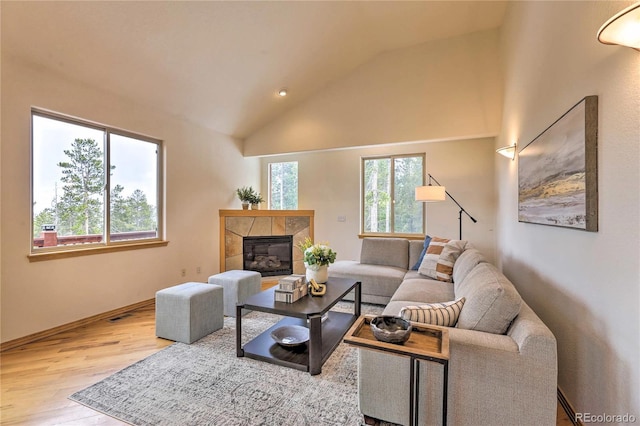 living room with light hardwood / wood-style flooring, a fireplace, plenty of natural light, and high vaulted ceiling