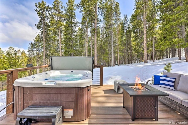 snow covered deck with an outdoor living space with a fire pit and a hot tub