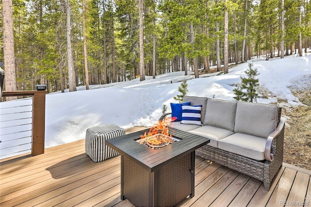 snow covered deck with an outdoor living space with a fire pit