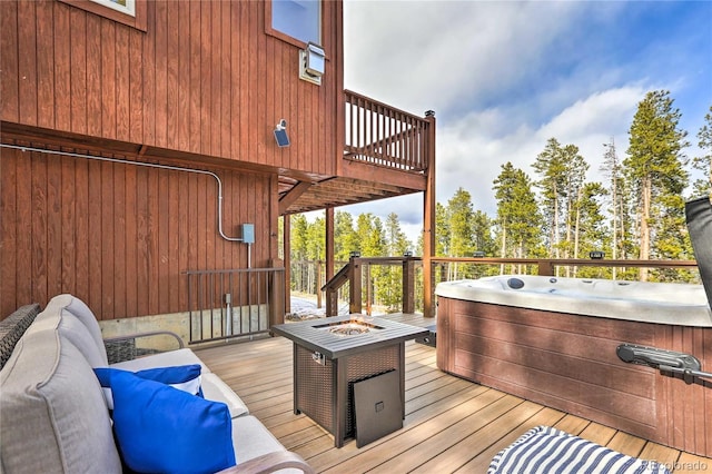 wooden deck featuring a hot tub and an outdoor living space with a fire pit