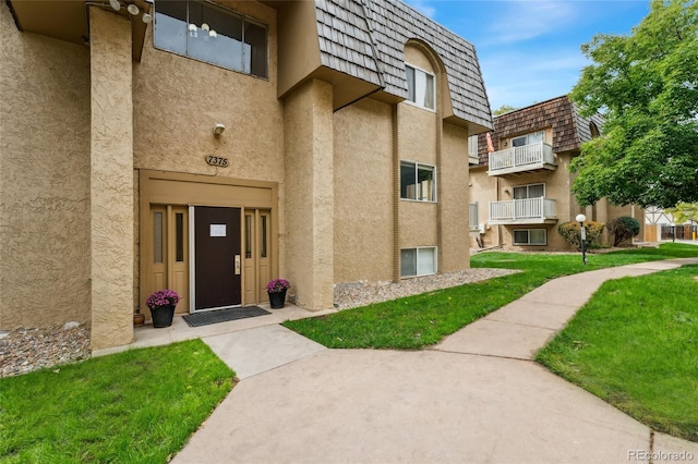 doorway to property featuring a lawn and a balcony