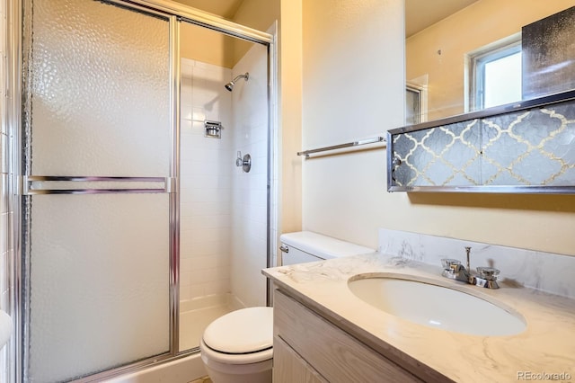 bathroom featuring toilet, a shower stall, and vanity