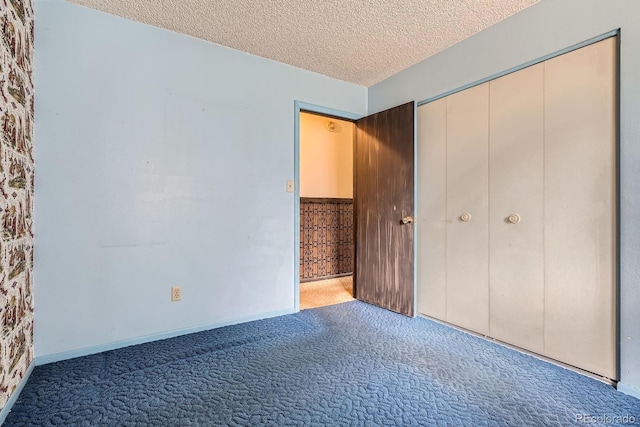 unfurnished bedroom with carpet, a textured ceiling, a closet, and baseboards