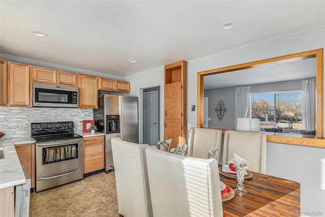 kitchen with appliances with stainless steel finishes, tasteful backsplash, and light tile patterned flooring