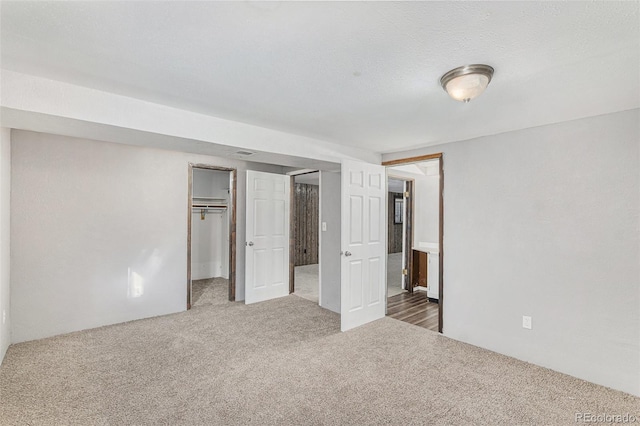 unfurnished bedroom featuring a walk in closet, a closet, and carpet