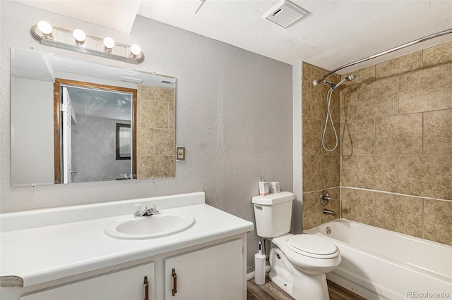 full bathroom with tiled shower / bath combo, wood-type flooring, a textured ceiling, toilet, and vanity