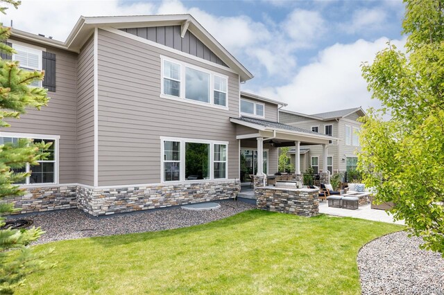 27653 E Euclid Dr, Aurora, CO 80016 - back of house featuring an outdoor living space with a fire pit, a patio area, a lawn, board and batten siding, and stone siding