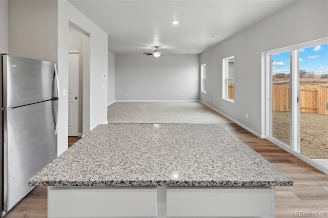 2145 Alyssa St, Fort Lupton, CO 80621 - kitchen with freestanding refrigerator, a ceiling fan, light stone counters, baseboards, and recessed lighting