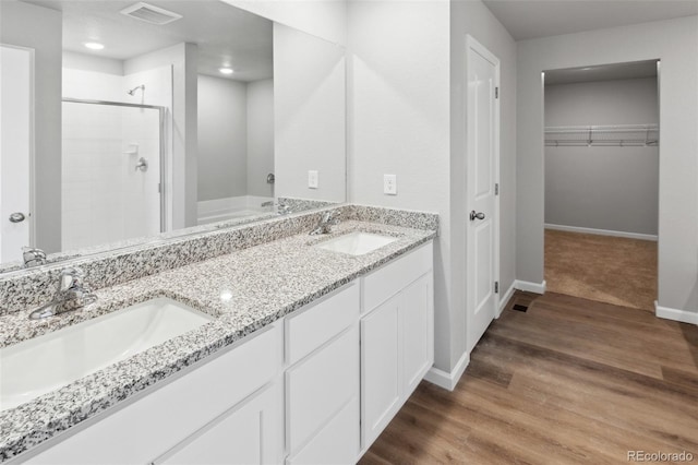2145 Alyssa St, Fort Lupton, CO 80621 - full bathroom featuring a stall shower, baseboards, a spacious closet, double vanity, and wood finished floors