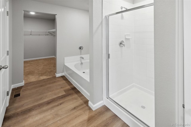 2145 Alyssa St, Fort Lupton, CO 80621 - full bathroom with a shower stall, a walk in closet, a bath, and wood finished floors