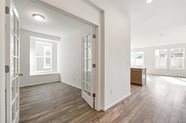 corridor with hardwood / wood-style flooring and french doors