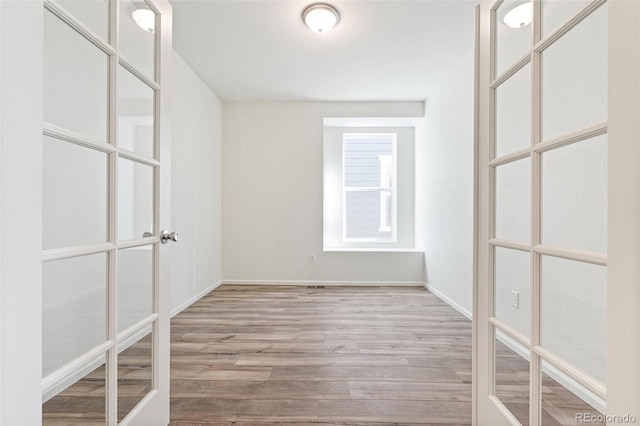 spare room featuring french doors and light wood-type flooring