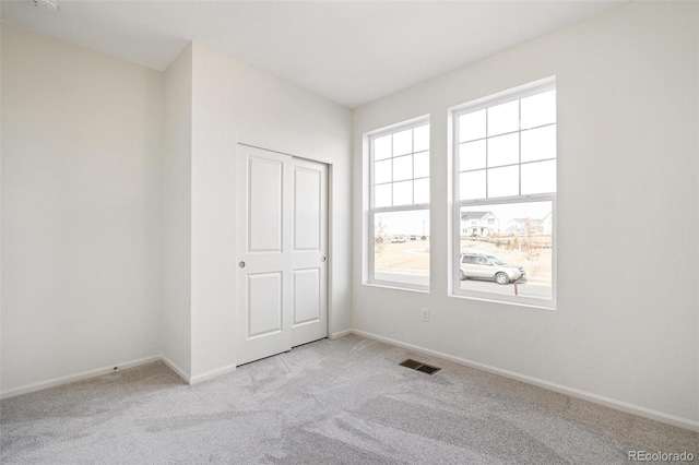 unfurnished bedroom with light colored carpet and a closet