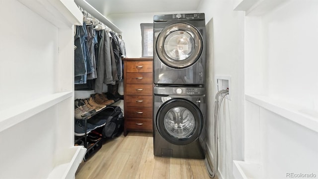 laundry room featuring stacked washing maching and dryer and light hardwood / wood-style flooring