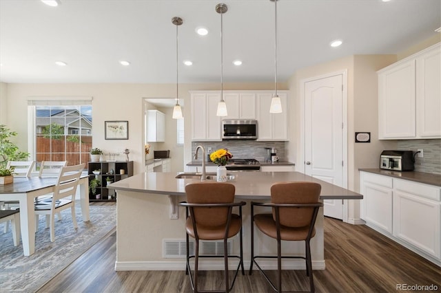 16341 Clayton St, Thornton, CO 80602 - kitchen with appliances with stainless steel finishes, dark wood-style floors, a center island with sink, decorative backsplash, and recessed lighting
