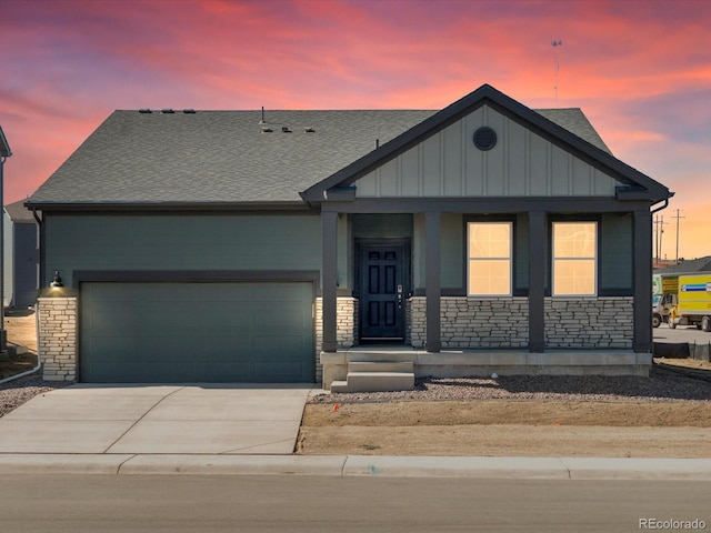 1634 Colorado River Dr, Windsor, CO 80550 - view of front of home featuring board and batten siding, driveway, stone siding, a porch, and a garage