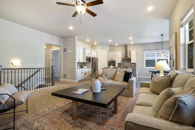 living room featuring sink, light colored carpet, and ceiling fan