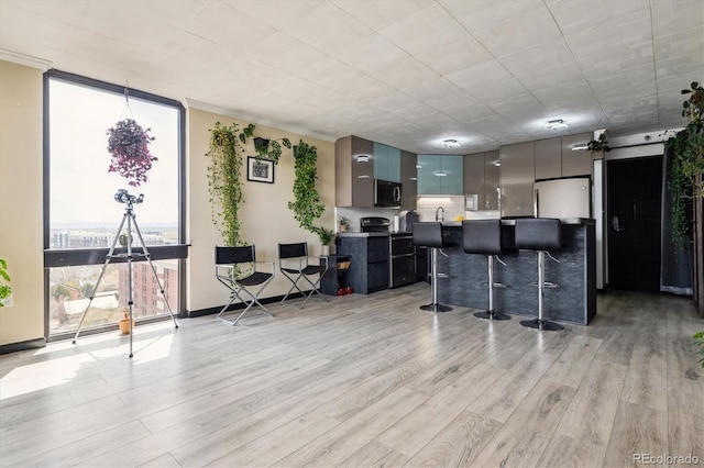 1301 Speer Blvd Unit 1108, Denver, CO 80204 - kitchen with modern cabinets, a kitchen bar, light wood-type flooring, light countertops, and expansive windows