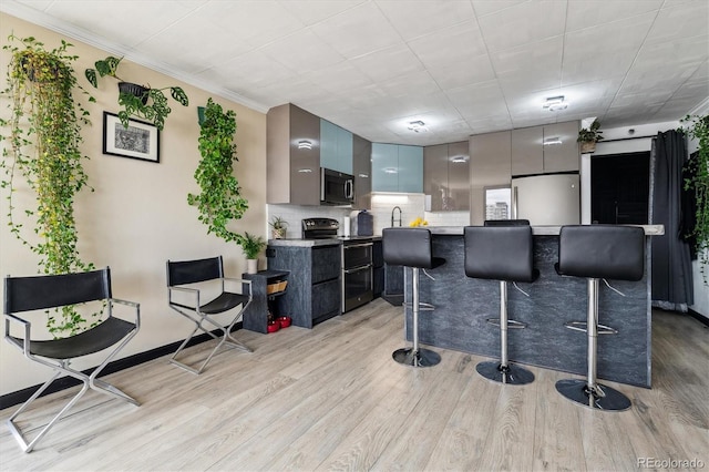 1301 Speer Blvd Unit 1108, Denver, CO 80204 - kitchen featuring stainless steel appliances, modern cabinets, a kitchen breakfast bar, light wood-style flooring, and tasteful backsplash