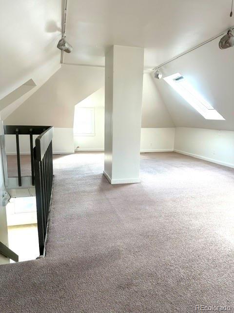 bonus room featuring carpet and vaulted ceiling with skylight