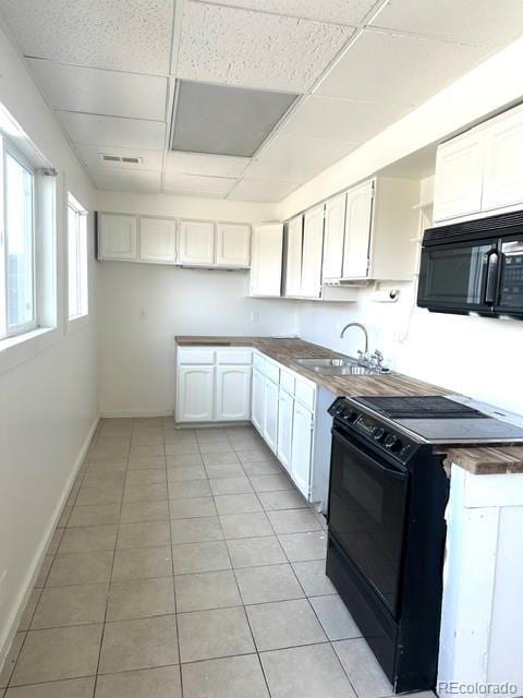 kitchen with white cabinetry, sink, butcher block countertops, a paneled ceiling, and black appliances