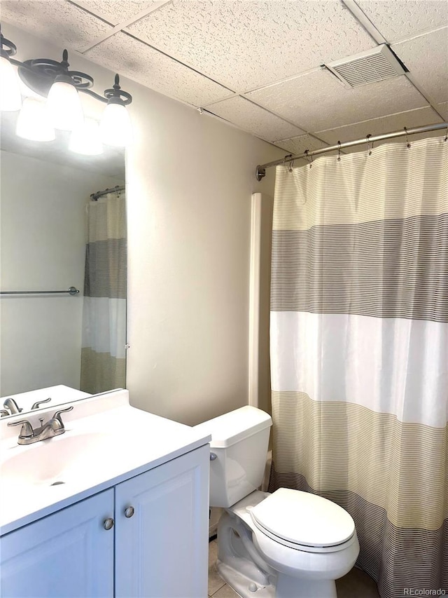 bathroom featuring a paneled ceiling, vanity, curtained shower, and toilet