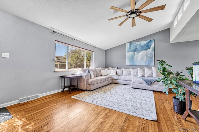 living room with ceiling fan, vaulted ceiling, wood finished floors, and baseboards