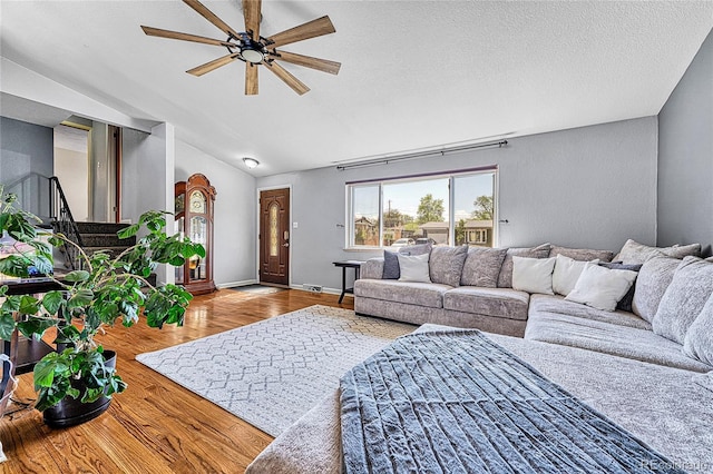living area with lofted ceiling, ceiling fan, wood finished floors, a textured ceiling, and baseboards