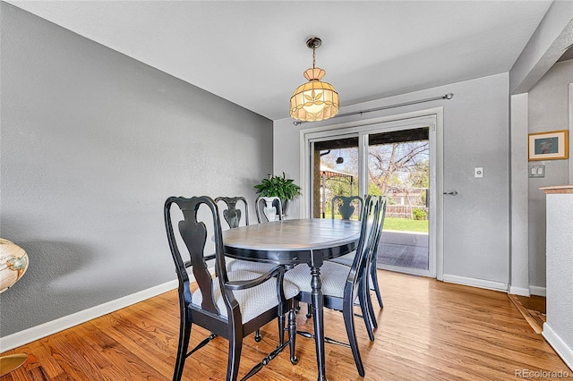 dining room with baseboards, light wood-style floors, and a textured wall