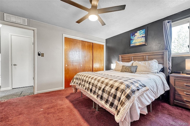 bedroom with dark colored carpet, a closet, ceiling fan, a textured ceiling, and baseboards
