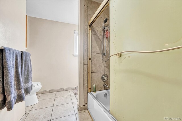 full bathroom with combined bath / shower with glass door, tile patterned flooring, toilet, and baseboards