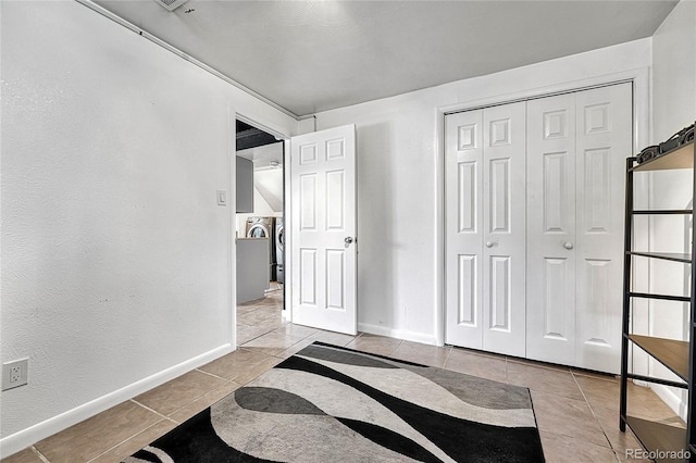 unfurnished bedroom with light tile patterned floors, baseboards, and a closet