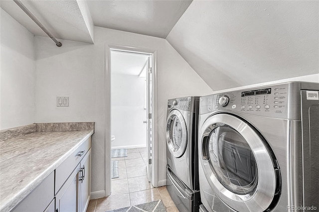 clothes washing area with separate washer and dryer, light tile patterned floors, and cabinet space