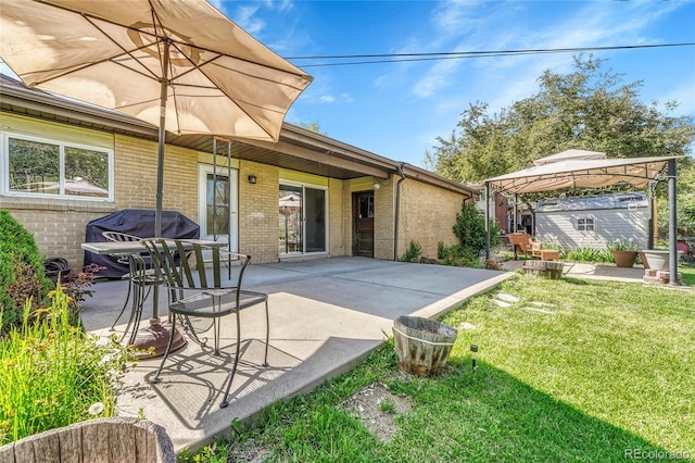 back of house with brick siding, a patio, a yard, and a gazebo