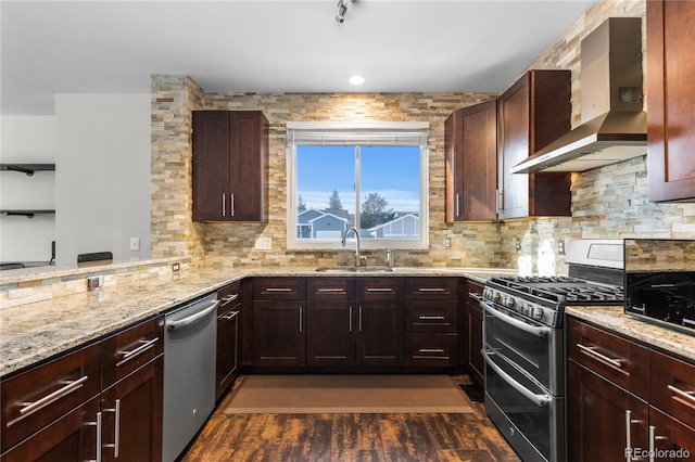 kitchen featuring light stone countertops, appliances with stainless steel finishes, wall chimney exhaust hood, dark hardwood / wood-style flooring, and sink