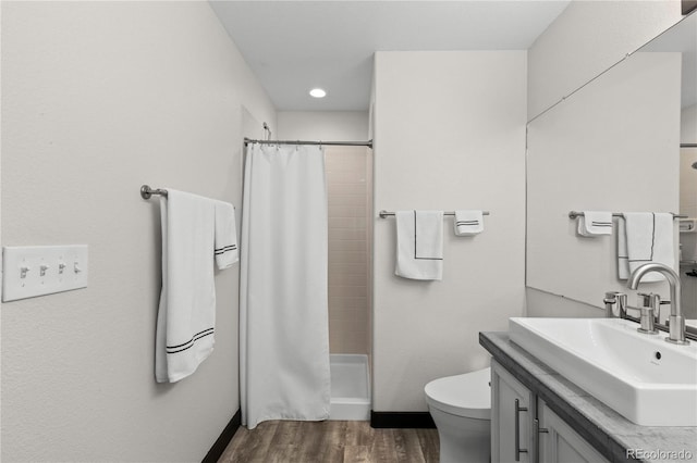 bathroom featuring wood-type flooring, toilet, walk in shower, and vanity