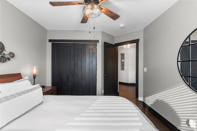 bedroom with ceiling fan, dark wood-type flooring, and a closet