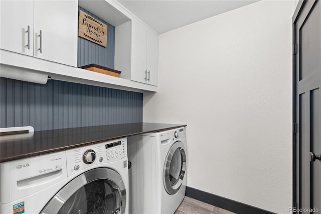 laundry area with cabinets, washing machine and dryer, and light hardwood / wood-style floors