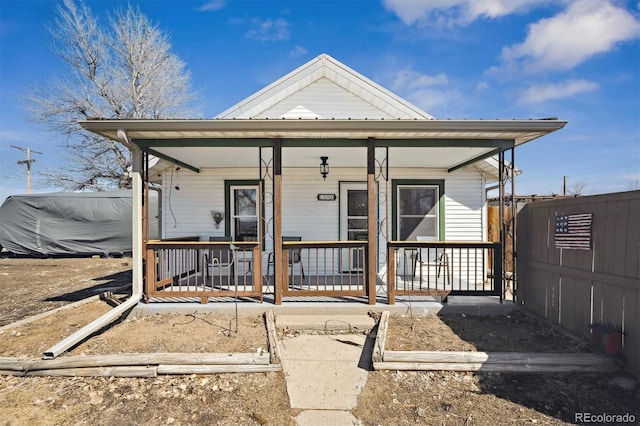 view of front of house featuring metal roof, a porch, and fence