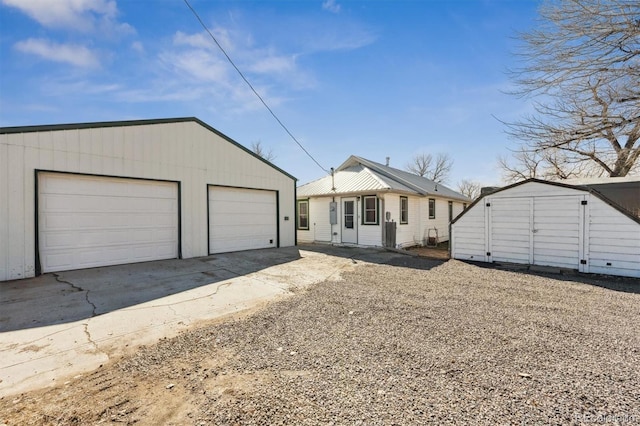 view of front of home with a detached garage and an outbuilding