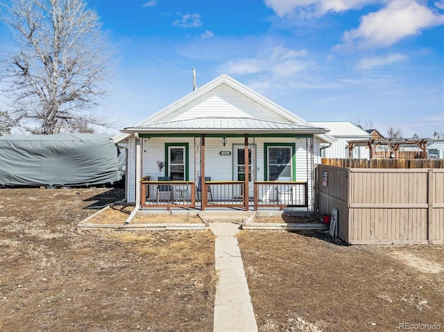 bungalow featuring covered porch, metal roof, and fence