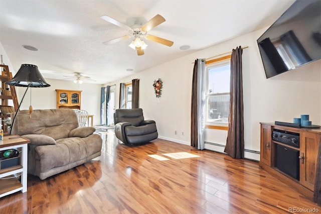 living room featuring wood finished floors, baseboards, a baseboard radiator, ceiling fan, and baseboard heating