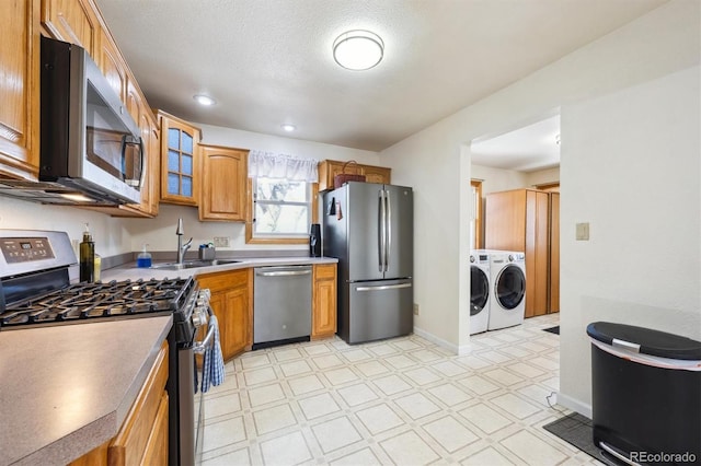 kitchen featuring a sink, light floors, appliances with stainless steel finishes, and separate washer and dryer