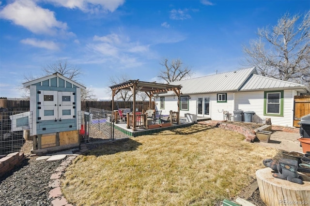 back of house with a lawn, metal roof, a fenced backyard, an outdoor structure, and a pergola