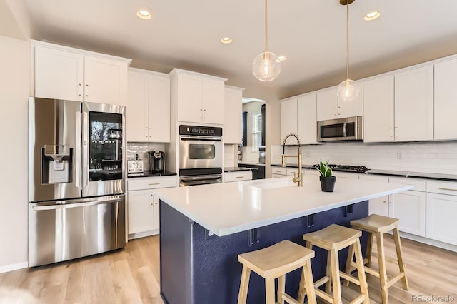 kitchen featuring stainless steel appliances, a sink, decorative backsplash, recessed lighting, and white cabinets