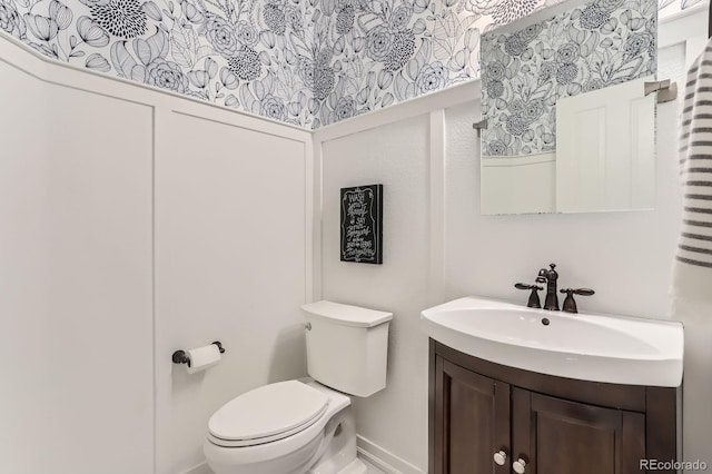 bathroom with toilet, vanity, and baseboards