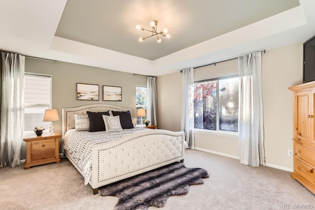 bedroom featuring a chandelier, light colored carpet, a raised ceiling, and baseboards